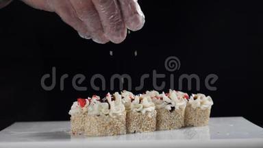 厨师用芝麻浇卷。 芝麻落在寿司卷上-慢动作镜头。 寿司板块收拢.. 高清高清